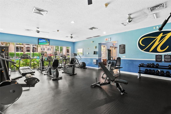 Indoor gym with exercise equipment, benches, and weights.
