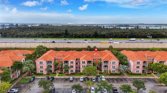 Aerial view of a residential complex with orange roofs near a highway and forested area.