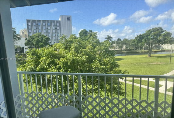 View from a balcony showing a tall modern building and lush greenery.