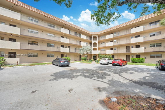 Front view of a multi-story residential building with parking area.