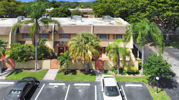 Front view of a multi-story townhouse with palm trees in front.
