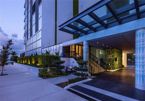 Front view of a modern multi-story building with glass facade and entrance walkway.