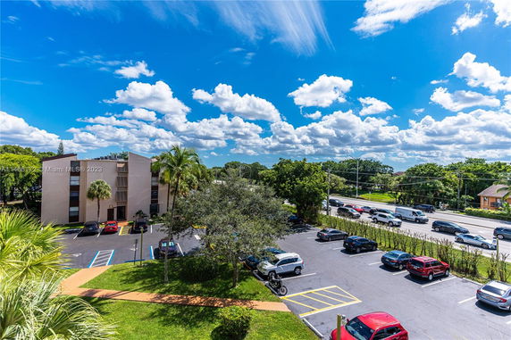 Outdoor parking lot with multiple cars and a building nearby.