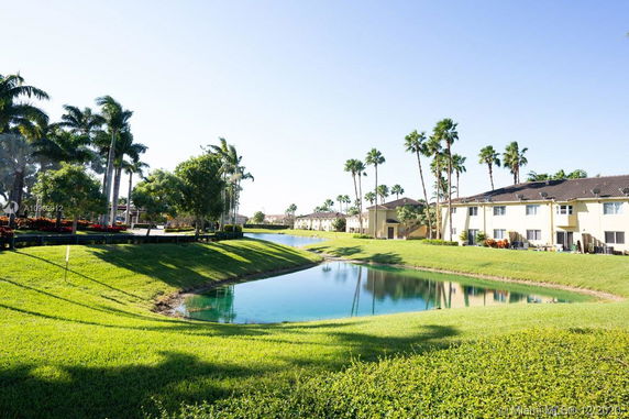 View of residential buildings with a pond and palm trees in the surroundings.