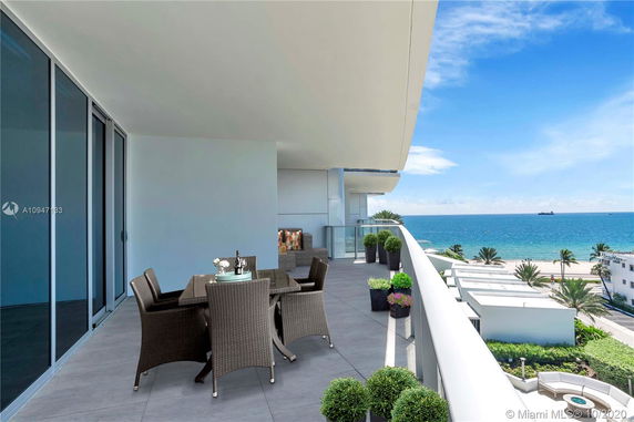 Balcony with outdoor seating overlooking the ocean and beach.