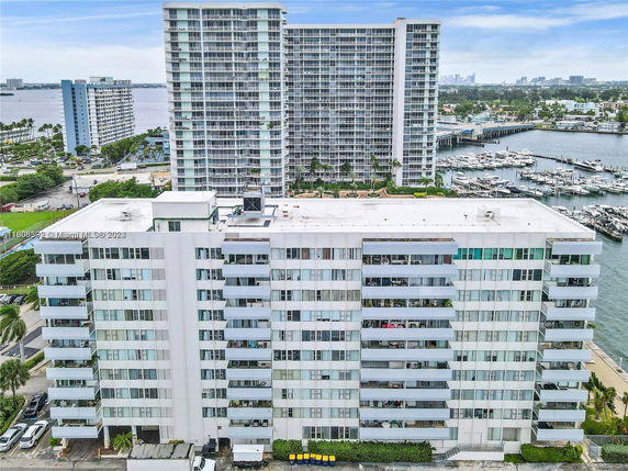 Front view of a multi-story apartment building with balconies overlooking a marina.