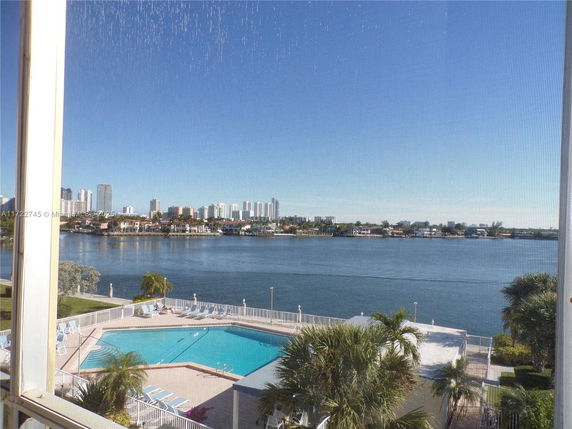 View of a swimming pool and waterway with cityscape in the background.