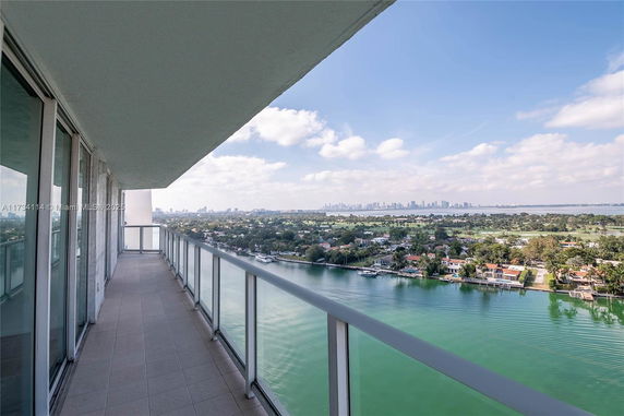 Panoramic view from a high-rise building balcony overlooking a body of water and city skyline.