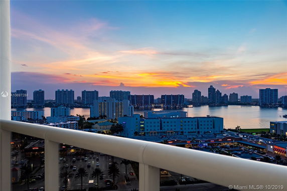 Panoramic view of a city skyline and water at sunset from a high vantage point.