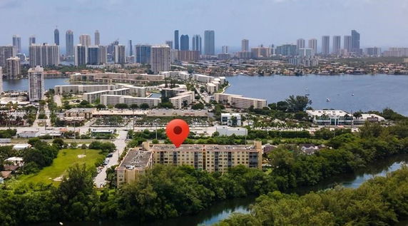 Aerial view of a cityscape with high-rise buildings, water bodies, and a marked location.
