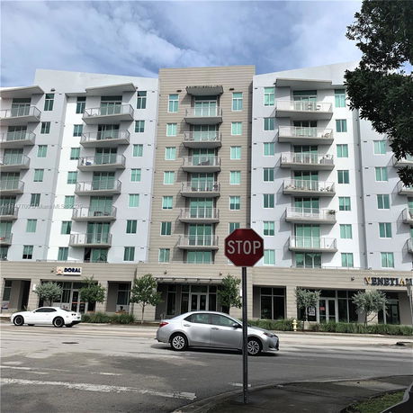 Front view of a multi-story apartment building with balconies and large windows.