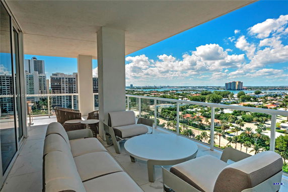 Panoramic view from a high-rise balcony overlooking a cityscape and body of water.