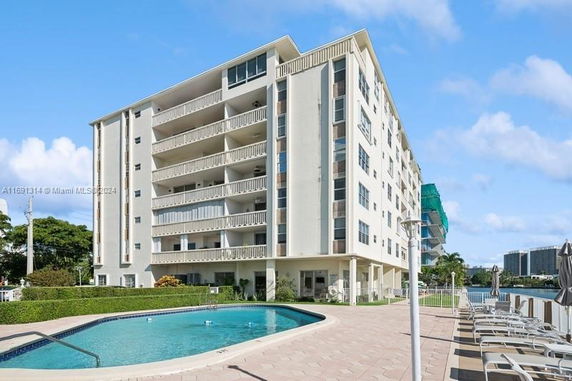 Outdoor swimming pool area adjacent to a multi-story residential building.