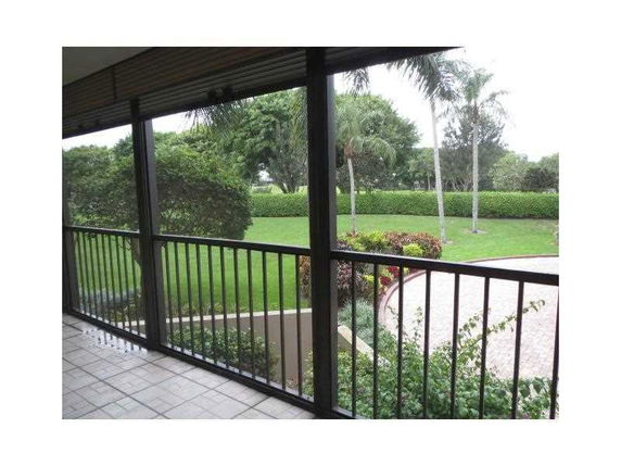 View from a balcony showing a well-maintained garden with palm trees and a circular driveway.