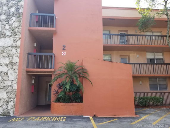 Front view of a multi-story building with balconies and a coral-colored exterior.