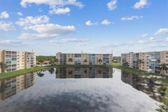 Panoramic view of apartment buildings surrounding a reflective pond.
