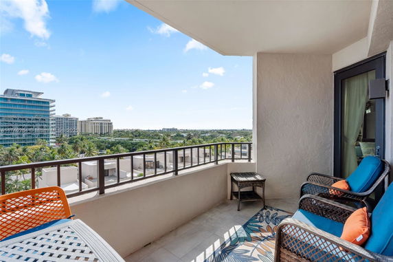 Balcony view with outdoor seating overlooking city buildings and greenery.