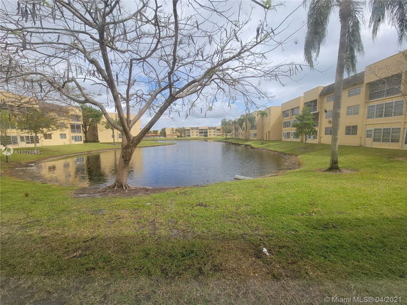 View of a pond surrounded by multi-story residential buildings.