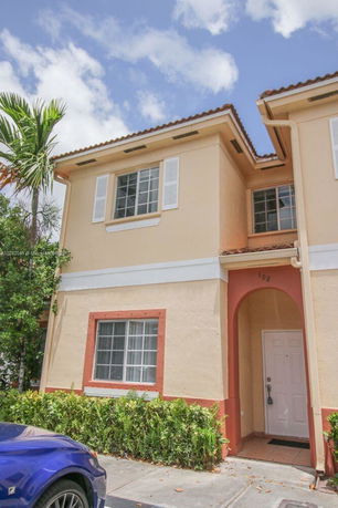 Front view of a two-story house with beige walls and red accents.