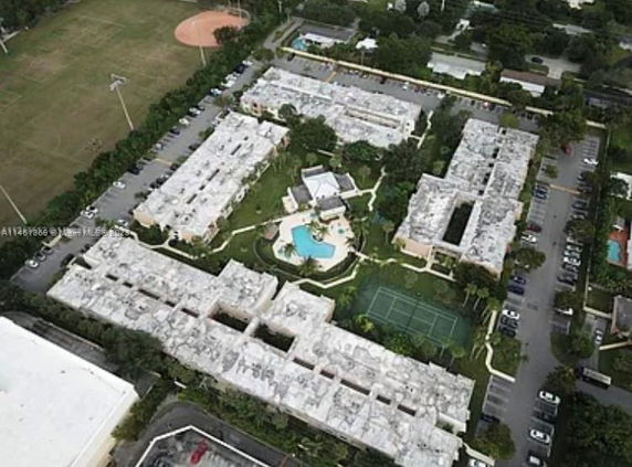 Aerial view of a residential complex with multiple buildings, a swimming pool, and tennis courts.