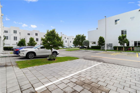 Outdoor parking area in front of white modern buildings.