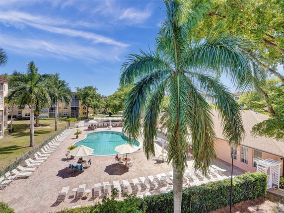 Outdoor swimming pool area with lounge chairs and umbrellas around the pool.