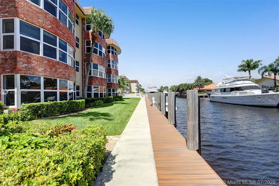 Front view of a multi-story building with large windows and a waterfront walkway.
