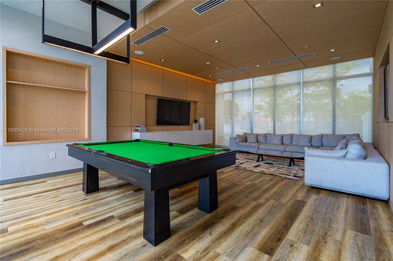 Room with a pool table, large sofa, and a television on the wall.