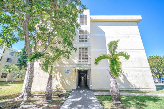 Front view of a multi-story building with trees surrounding the entrance.