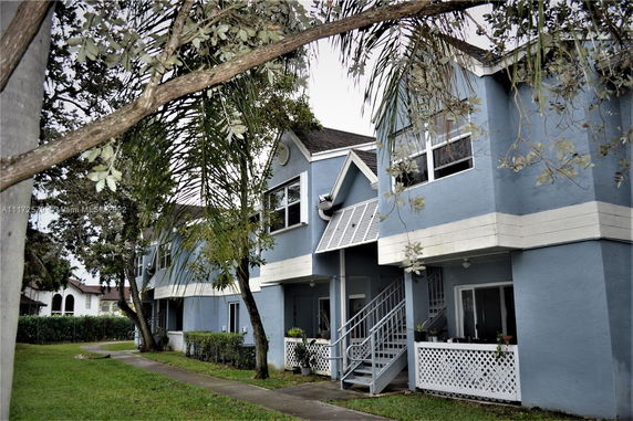 Front view of a two-story blue apartment building with external staircases.