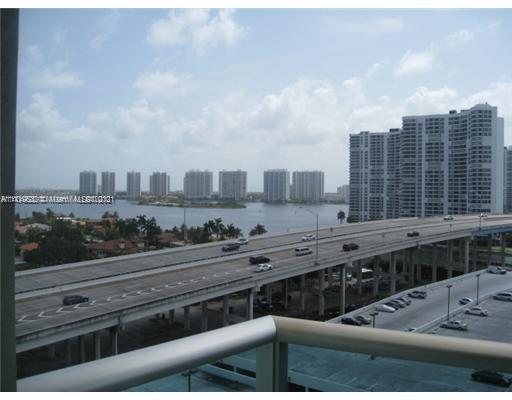 View of a highway with cars, a body of water, and high-rise buildings in the background.