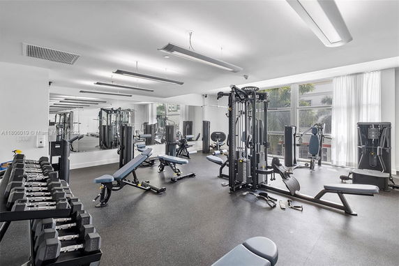 Interior view of a gym with various exercise equipment and mirrors on the wall.