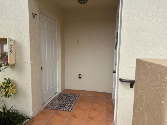Entrance view of a building with a beige door and tiled floor.