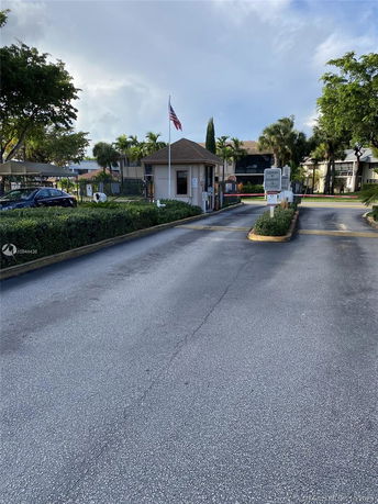 Gated entrance to a residential complex with guard booth.