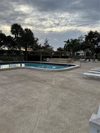 Outdoor swimming pool area with deck chairs and surrounding trees.