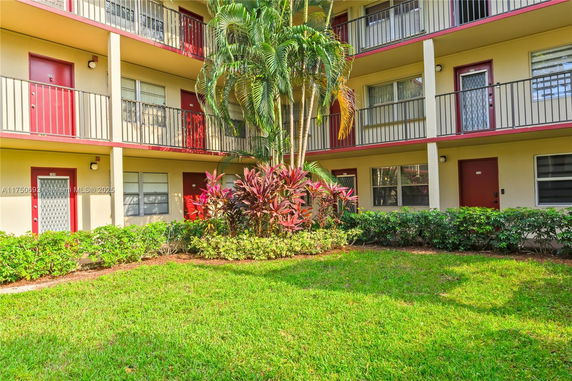 Exterior view of a multi-story building with balconies and a small garden area.