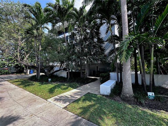 Front view of a house partially obscured by trees and vegetation.
