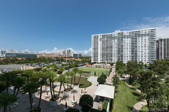 View of a large apartment complex with multiple floors, surrounded by landscaping and outdoor amenities.