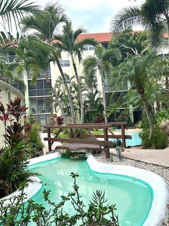 Outdoor view of a residential building with a pool and palm trees.