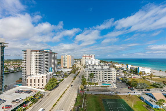 Aerial view of high-rise buildings along a coastal road with the ocean in the background.