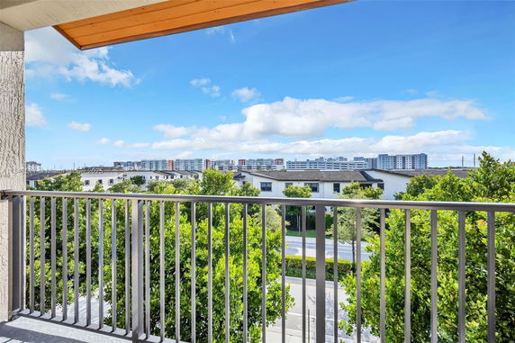 View from a balcony showing distant high-rise buildings and a clear sky.
