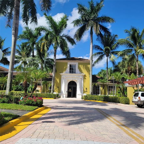 Front view of a two-story house with palm trees and a driveway.