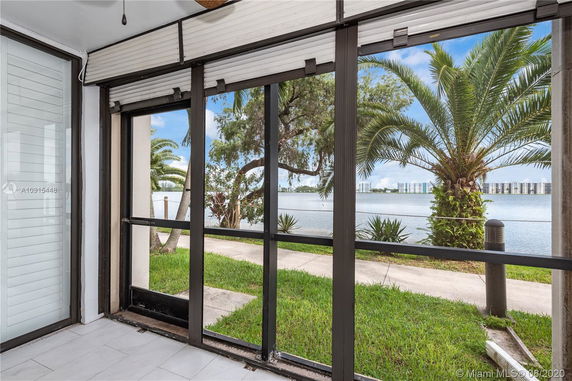 View of surrounding area with palm trees and water body visible through glass panels.