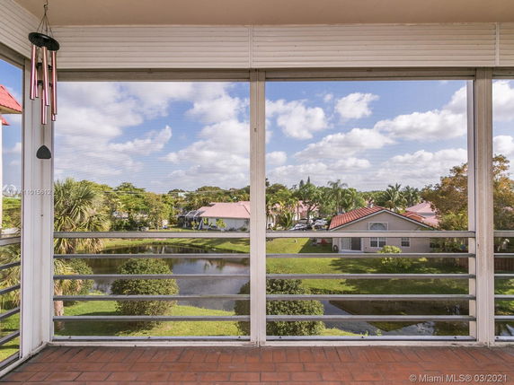 Panoramic view of residential area with houses, palm trees, and a small pond.