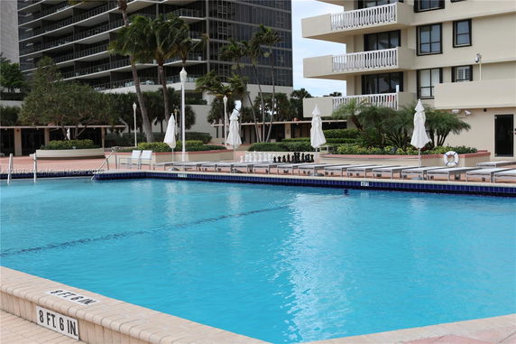 View of a pool area in front of a multi-story building with balconies.