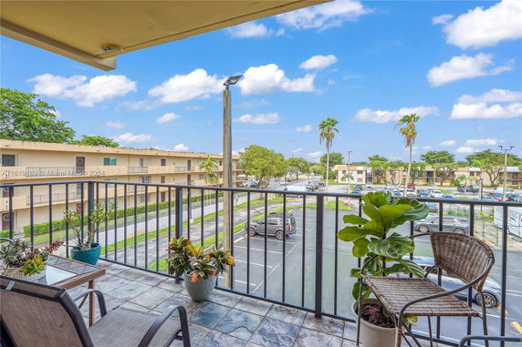 View from a balcony showing a parking area and surrounding apartment buildings.
