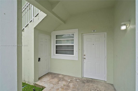 Front view of an apartment entrance with white doors and a window.