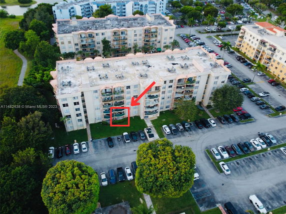 Aerial view of a multi-story apartment building with a flat rooftop featuring air conditioning units.