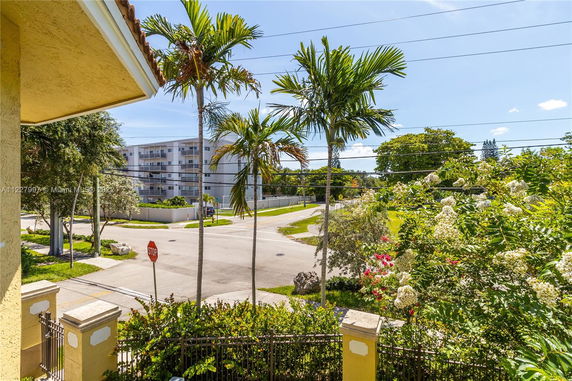View from a building showing a street, palm trees, and an adjacent apartment complex.