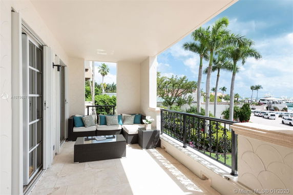 Balcony view from a building overlooking palm trees and a marina.